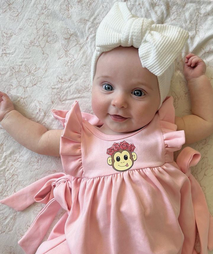 baby girl wearing a cute pink dress with frill sleeves and tie-up bows on the side. 