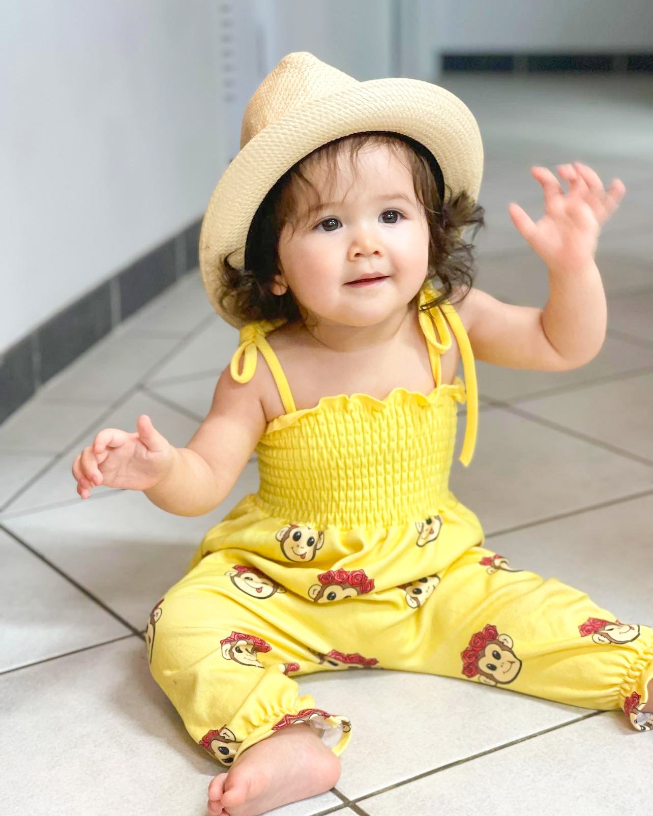 baby girl wearing a cute yellow jumpsuit with monkeys on it