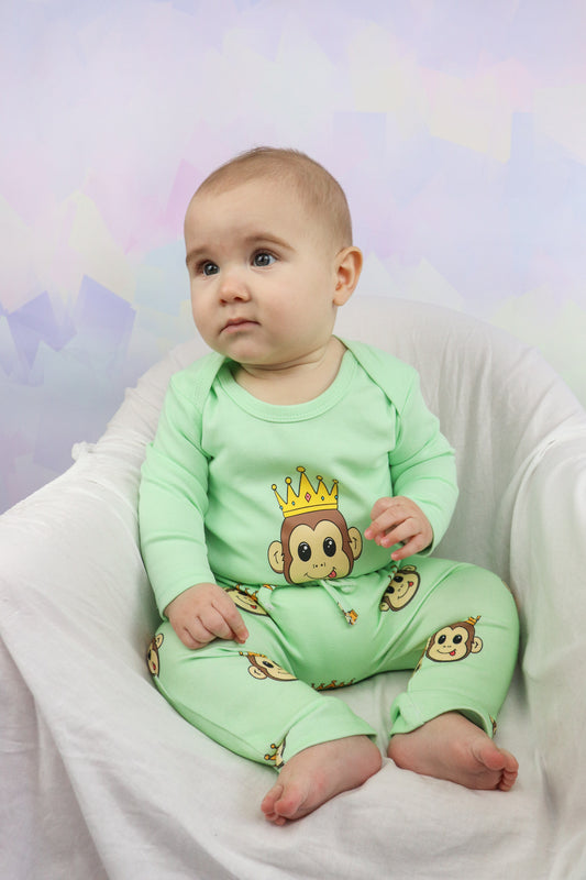 baby boy sitting on a chair wearing a pastel green long sleeve romper with a cute monkey design. Also wearing pastel green pants with the cute monkey design printed all over