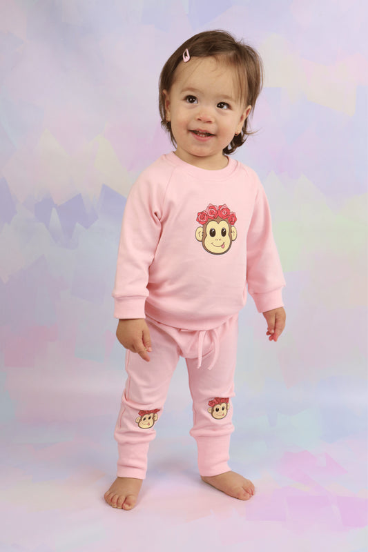 toddler girl wearing a pastel pink lounge set with cute monkey faces printed on it